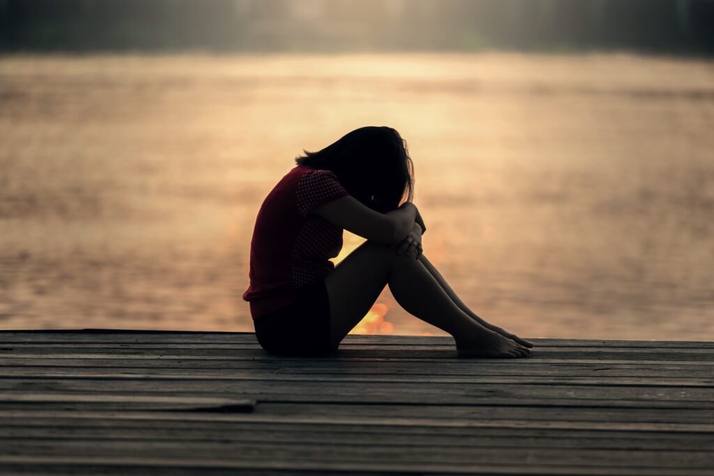 Persona rannicchiata al tramonto, metafora di solitudine e depressione