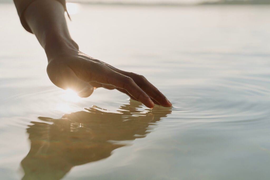 Metafora visiva del contatto emotivo nel percorso psicologico: una mano sfiora delicatamente la superficie dell'acqua creando