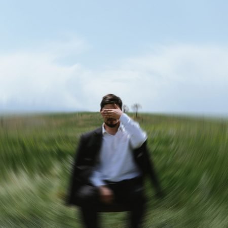 Uomo nel prato in uno stato di sovraccarico emotivo e ansia