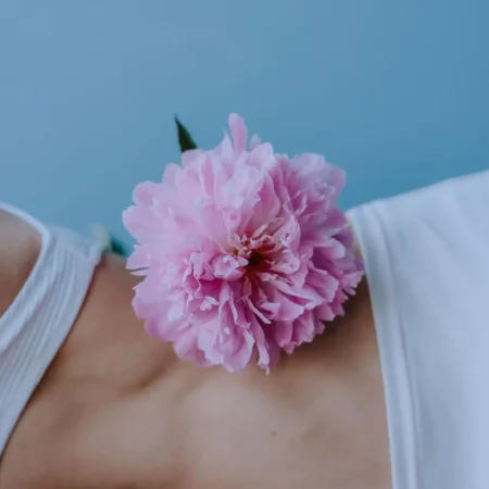 Fiore rosa sul corpo, simbolo di delicatezza, cura di sé e rinascita, supporto per il disagio corporeo