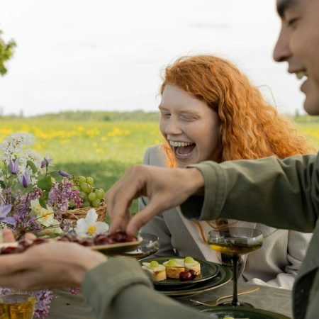 Persone sorridenti che condividono il cibo all'aperto, simbolo di serenità a tavola, libertà dai sensi di colpa e